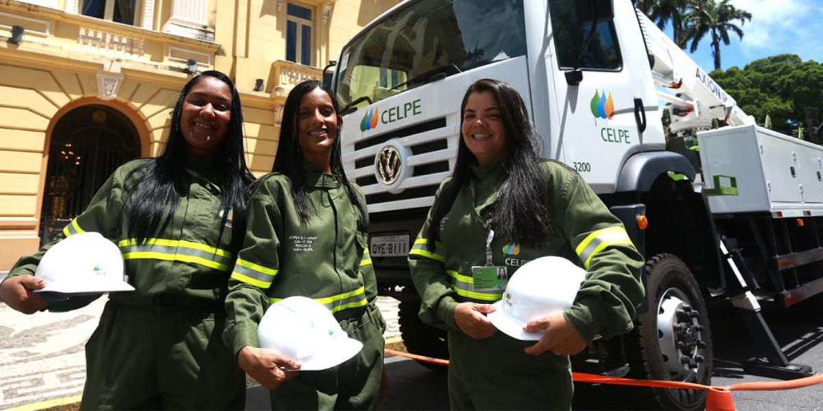 Três mulheres do Jovem Aprendiz Celpe 2024 em frente a um caminhão da companhia